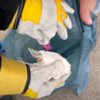 Videostill Kinderhände mit Handschuhen die Müll in einen Müllsack geben