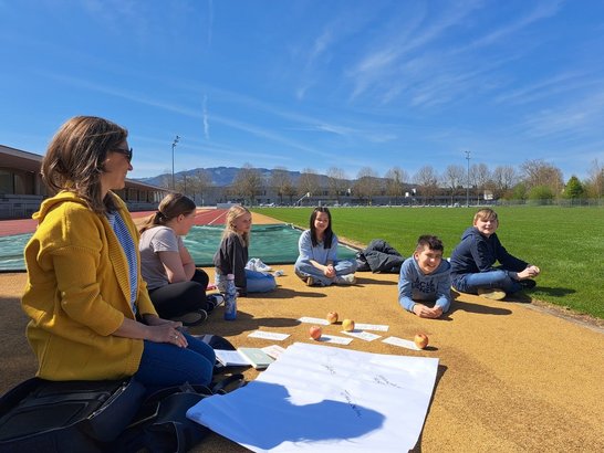 Kinder mit ihrer Lehrerin auf einem Sportplatz