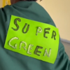 Am Rücken ist ein neongrüner Zettel mit goldener Schrift super green angeheftet