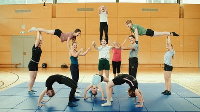 Mehrere Kinder tanzen und machen Turnübungen in einer Sporthalle