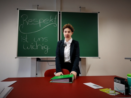 Schüler:in steht vor einer Tafel mit der Aufschrift „Respekt ist uns wichtig“.