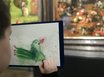 Ein Kind malt einen grünen Vogel auf einem Bildschirm