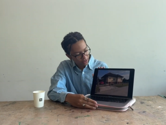 Schüler:in präsentiert an einem Laptop eine Aufnahme eines Wohnhauses.