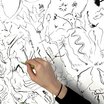Hand mit Stift zeichnend auf weiße Fläche voller schwarzer Linien