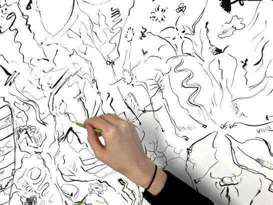 Hand mit Stift zeichnend auf weiße Fläche voller schwarzer Linien