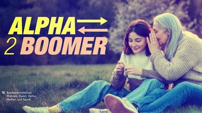 Eine Schülerin und eine Seniorin sitzen auf einer Wiese