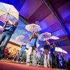 Kinder stehen auf einer Bühne, sie halten Regenschirme