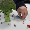 Ein Brokkoli auf einem weißen Tisch mit kleinen Spielzeugfiguren