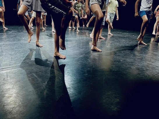 Viele Beine auf einer Bühne in Mitten einer Choreographie. 