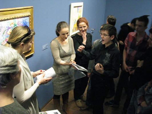 Foto von einem Schüler, der die erarbeitete Broschüre im Museum präsentiert