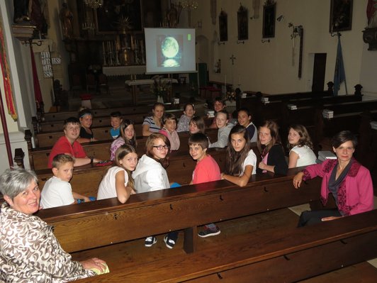 Foto einer Gruppe SchülerInnen in der Kirche vor einer Leinwand mit einem Foto des Mondes