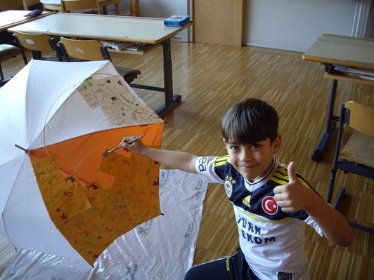 Foto von einem Schüler mit einer Regenschirmskulptur mit verschiedenen Sprachen