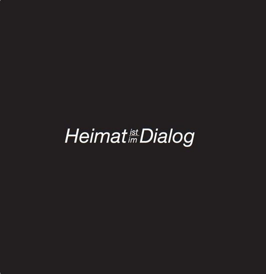 ''Heimat ist/im Dialog'' in weißer Schrift auf schwarzem Grund