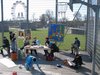 Foto von SchülerInnen, die  ein Klassenzimmer im öffentlichen Raum vor der Kulisse des Wiener Riesenrades rekonstruieren