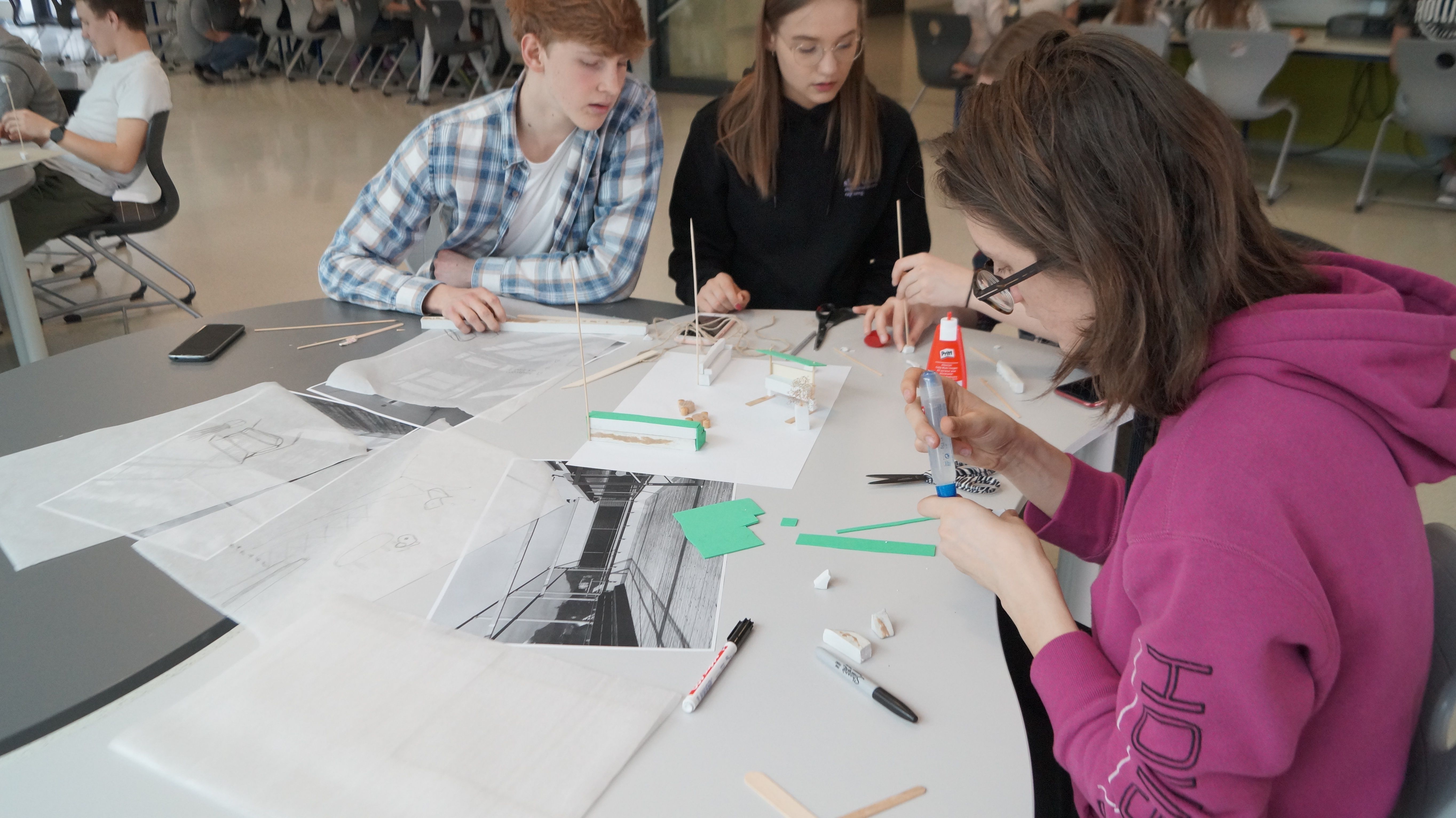 Foto von zwei Schülerinnen und einem Schüler, die ein Architekturmodell bauen