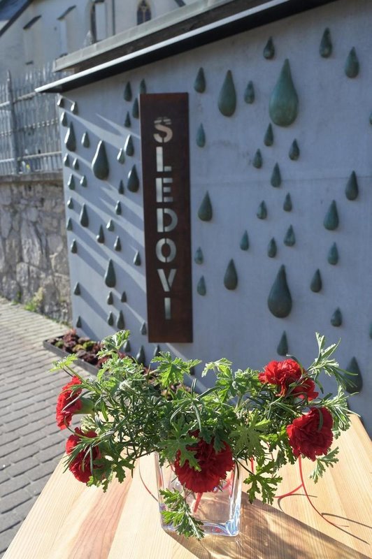 Wand voller Tropfen-Skulpturen mit Blumenstrauß auf Tisch im Vordergrund