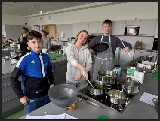 Drei Schüler/innen kochen in einer Küche