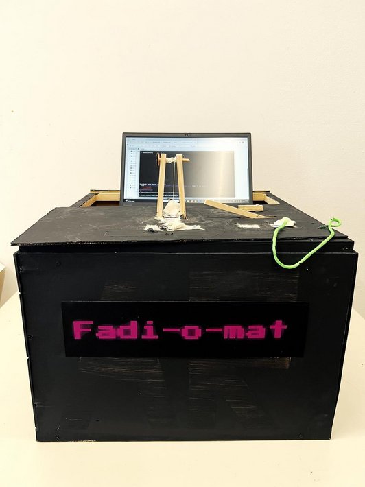 Foto einer schwarzen Kiste aus Holz einem Monitor mit Programmiercodes und einer Holzvorrichtung mit einer Kurbel, Faden und Stein.