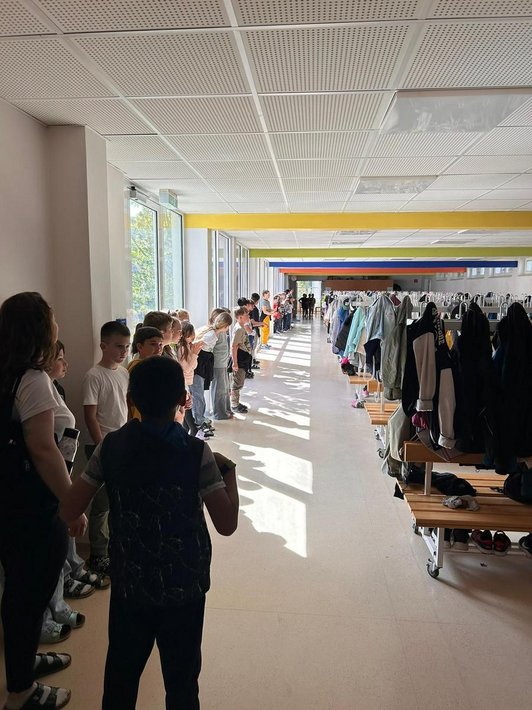 viele Schüler/innen stehen in Garderobenraum aufgereiht