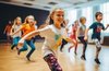 Fröhliche Kinder tanzen im Turnsaal in einer Reihe.
