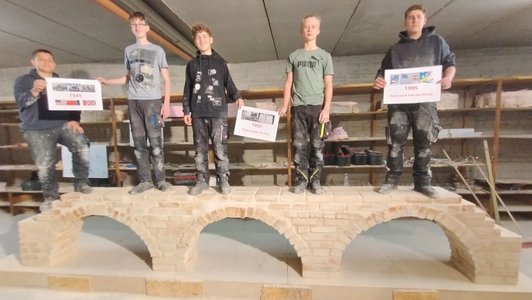 5 Schüler stehend auf einer selbst gemauerten Brücke