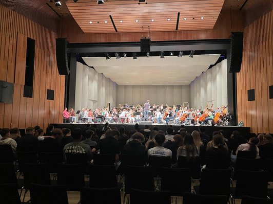 Blick auf die Bühne mit musizierenden Kindern und Jugendlichen und Publikum