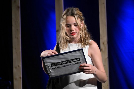 Schülerin hält und blickt auf Klammbrett