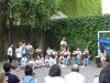 Kinder mit weißen T-Shirts auf denen H2O steht, spielen auf Dzemben und Trommeln im Hof einer Schule