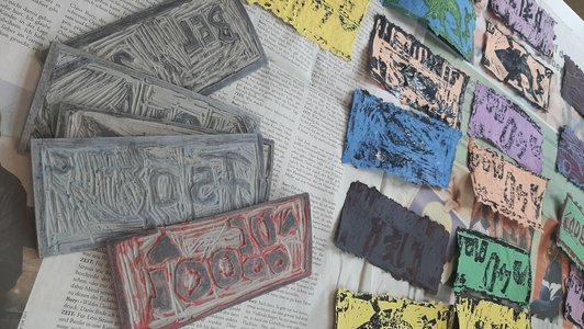 Foto von selbst geschöpften Altpapier und gedrucketen Geldscheinen und Linolplatten.