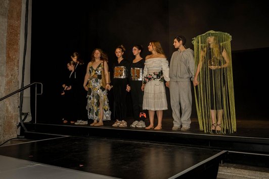 Foto der Fashionshow. Mit  sein´ben Schülerinnen in unterschiedlicher Kleidung ind gold/schwarz und weiss