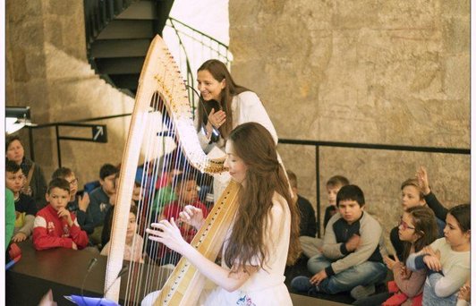 Kinder lauschen einer Harfenspielerin in der Virgilkapelle.