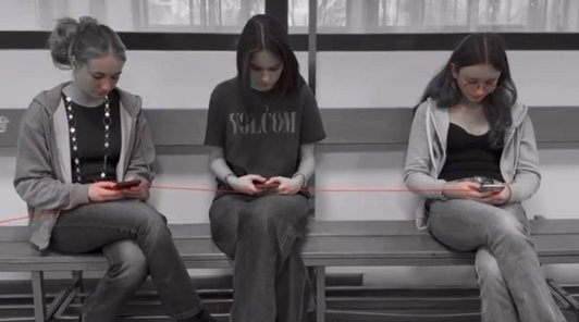 Schwarz-weiß- Foto von drei Schülerinnen mit Handy durch einen roten Faden verbunden.