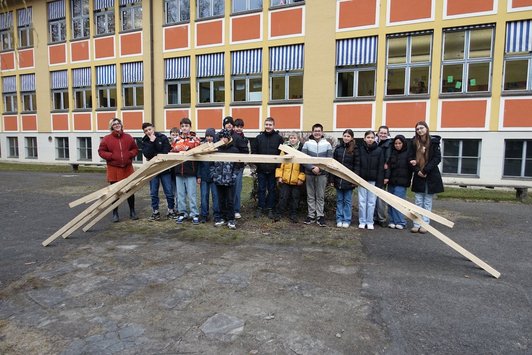 Foto von einer Klasse vor der Schule mit selbst gebauter Brücke.
