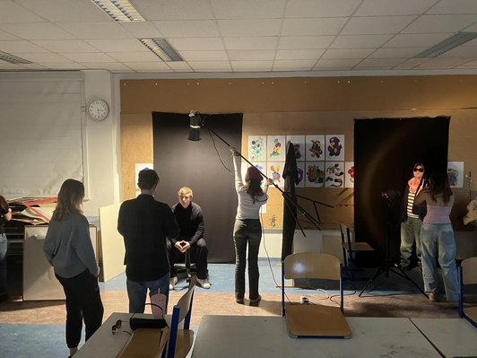zwei schwarzen Tüchern an Klassenzimmer-Wand vor denen Schüler/innen einander fotografieren
