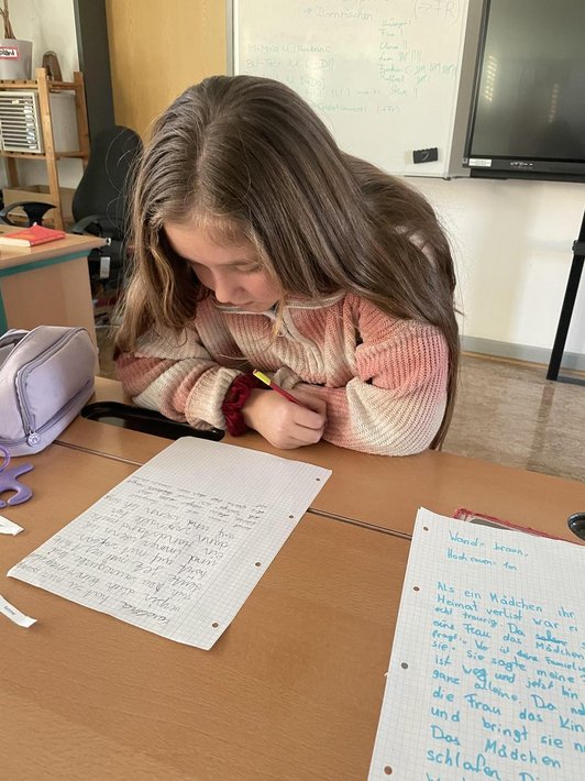 Mädchen sitzt mit Rotstift über Papierblatt voller Handschrift