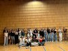 Mädchen einer Klasse stehen vor einer Holzwand im Turmsaal und heben die Arme "Zusammen sind wir stark".