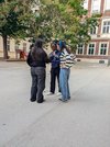 Ein Mädchen im Schulhof richtet ein Mikrophon einem anderen Mädchen  hin. Das Dritte nimmt die Aufnahme auf.