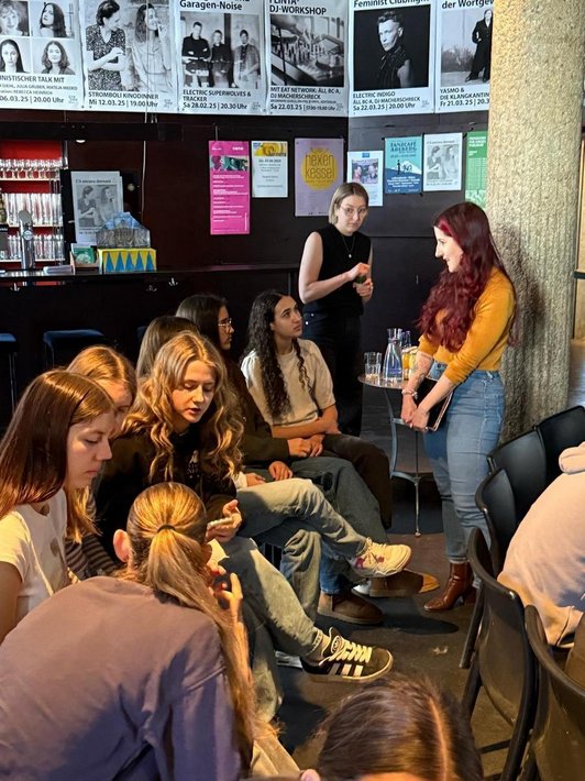 Schüler/innen diskutieren intensiv vor einem Kaffeehaustisch