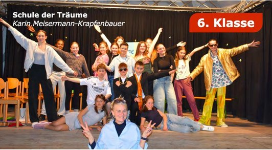 Plakat mit einer Szene aus einem Theaterstück mit der gesamten Schüler/innengruppe und Text "Schule der Träume" 6. Klasse. 