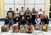Foto von Schüler:innen mit quadratischen Kartonschachteln als Hocker mit unterschiedlichen Pixelbildern bemalt.