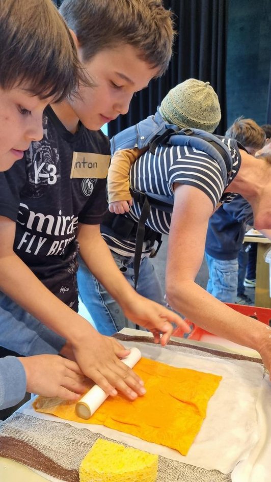 zwei Schüler pressen mit Handrolle durch Tücher