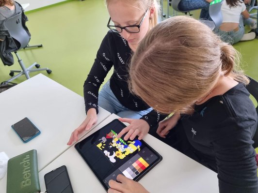 Foto von zwei Schülerinnen, die mit dem iPad malen und animieren