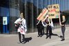 Foto von sechs Lehrlingen mit Masken und zwei Transparenten bei der Performance neben dem Lentos 