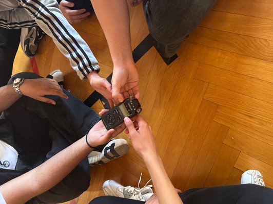 Vier Händer, die ein Aufnahmegerät halten