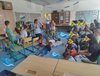 Acht Kinder spielen auf Stühlen und am Boden ein Schiffmit einer Mannschaft im Meer und weitere Kinder schauen zu.