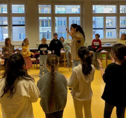 Eine Rapperin steht mitten im Raum und animiert die Schüler/innen sich zu bewegen.