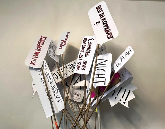 Tafeln mit handgeschriebenen Kommentare sind an eine Wand gelehnt.