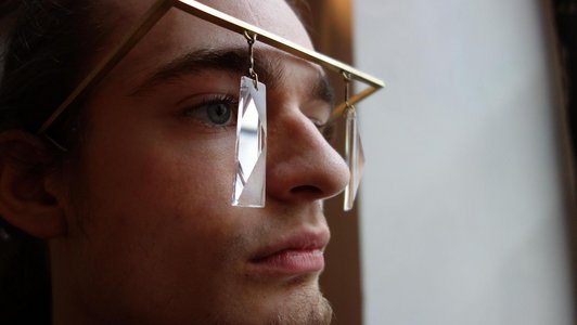 Gestaltete Brille mit rechteckigem Glas und goldenem Gestell.