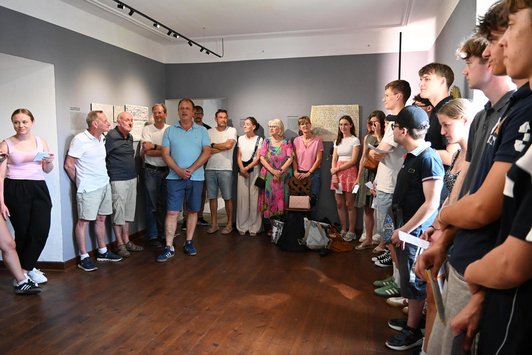 Jugendliche und Erwachsene stehen in Ausstellungsraum im Kreis