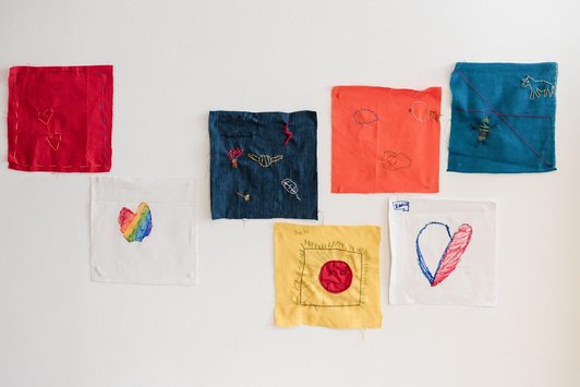 7 bunte Stoffquadrate mit aufgestickten Motiven